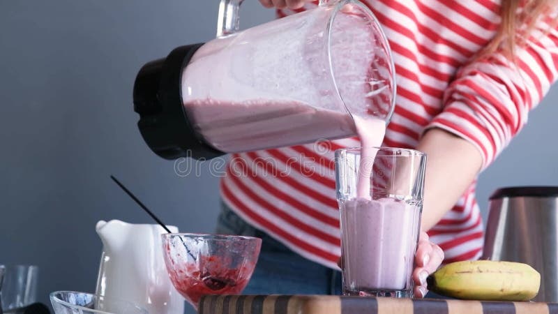 женщина делает молочный коктейль с бананом и мороженым в блендере видеоматериал