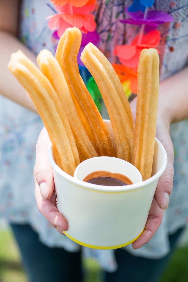 Женщина держа бумажный стаканчик заполнила с churros и погружением шоколада стоковые изображения rf Женщина держа бумажный стаканчик заполнила с churros и погружением шоколада стоковые изображения rf