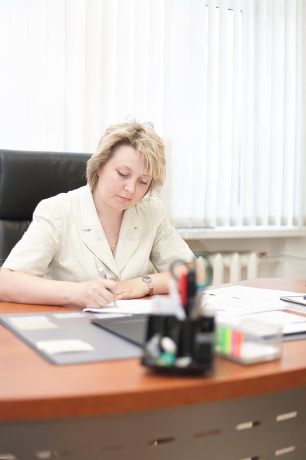 Mid-life business woman sign document in office. Mid-life business woman sign document in office