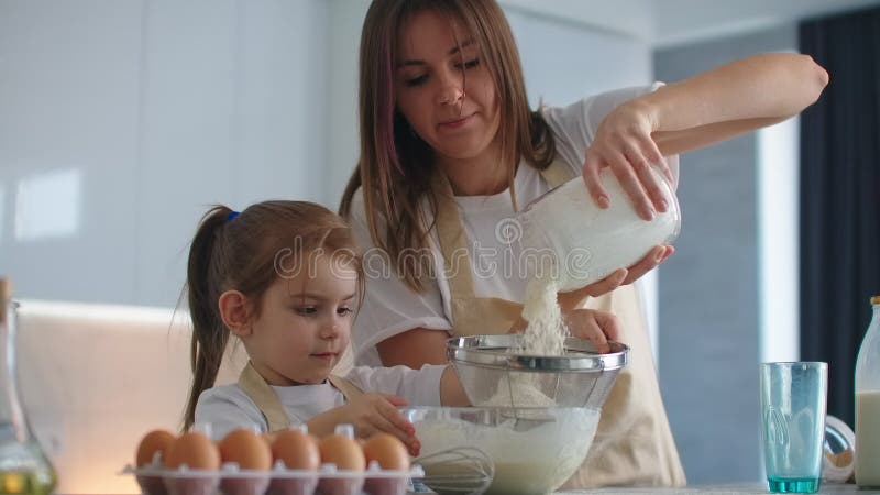 Женщина и девочка юркнуть яйца на кухне. Дочь и мать готовит вместе акции видеоматериалы