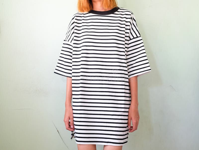 Женщина моды в striped платье на белой стене стоковая фотография Женщина моды в striped платье на белой стене стоковая фотография