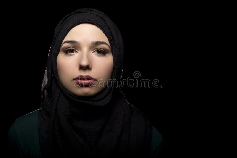 Proud and confident female wearing a black hijab as a conservative fashion choice to represent feminist freedom of expression and political statement. The headscarf is associated with muslims and middle eastern and east eauropean culture. Proud and confident female wearing a black hijab as a conservative fashion choice to represent feminist freedom of expression and political statement. The headscarf is associated with muslims and middle eastern and east eauropean culture.