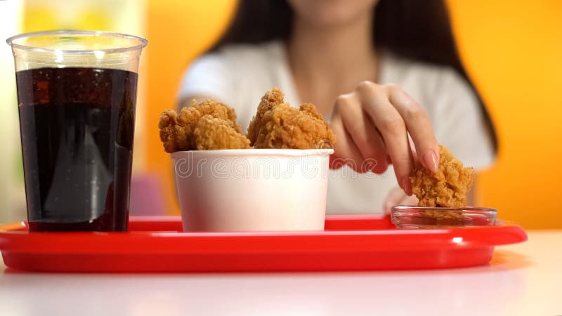 Женщина окуная хрустящие крылья жареной курицы в крупном плане соуса кетчуп, хрустящей закуске стоковые фотографии rf Женщина окуная хрустящие крылья жареной курицы в крупном плане соуса кетчуп, хрустящей закуске стоковые фотографии rf