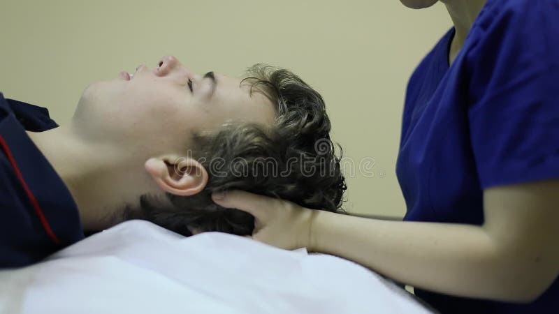 женщина-остеопатик держит голову мальчика видеоматериал