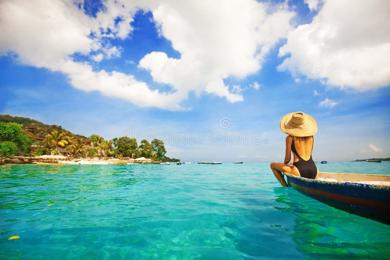Back view of a woman sailing a boat in a paradise island. Back view of a woman sailing a boat in a paradise island