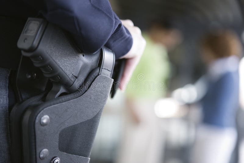 Female police sergeant standing with gun in hand. Female police sergeant standing with gun in hand.