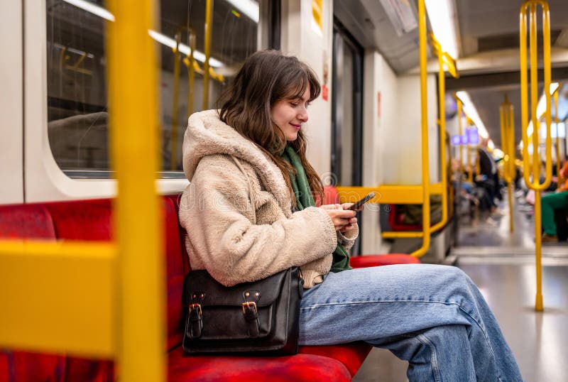Женщина пользуется телефоном во время езды на метро стоковые фото