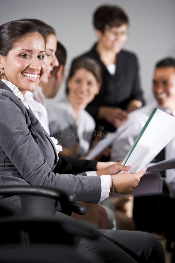 Young business people or college students sitting in row reading report in presentation. Young business people or college students sitting in row reading report in presentation