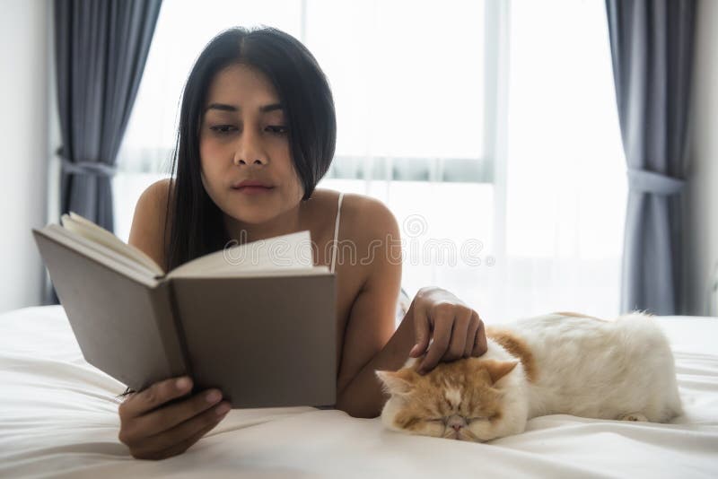женщина прочитала книгу и кот игры на кровати стоковые фотографии rf женщина прочитала книгу и кот игры на кровати стоковые фотографии rf