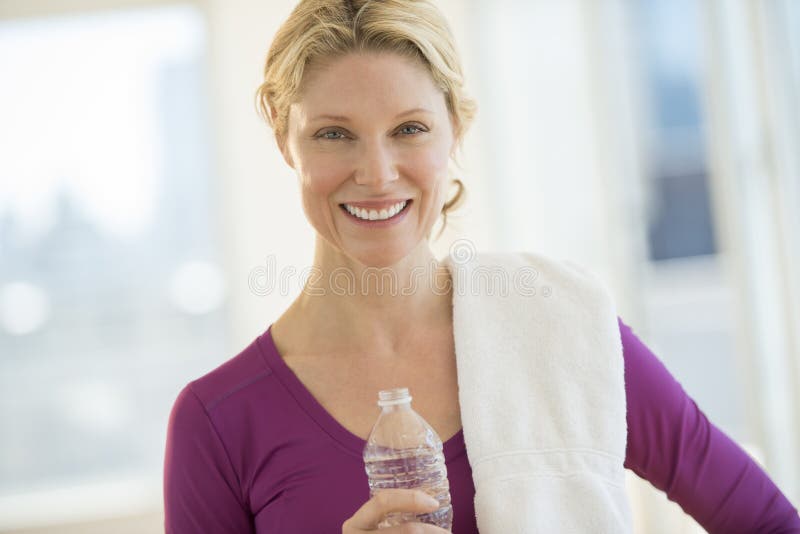 Portrait of beautiful mature woman with water bottle and towel smiling in health club. Portrait of beautiful mature woman with water bottle and towel smiling in health club