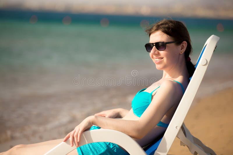 Женщина сидя на deckchair солнца стоковое изображение rf Женщина сидя на deckchair солнца стоковое изображение rf