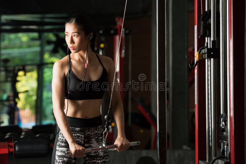 Женщина фитнеса, азиатская женщина изгибая руку muscles на машине кабеля стоковые фото Женщина фитнеса, азиатская женщина изгибая руку muscles на машине кабеля стоковые фото