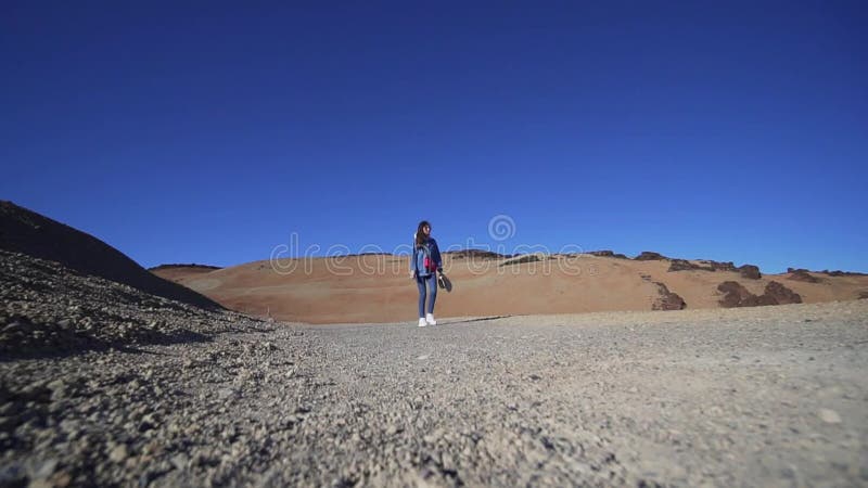 Женщина-хипстер проходит мимо камеры через вулкан, пустыню, засушливый климат Статический выстрел, широкий угол
