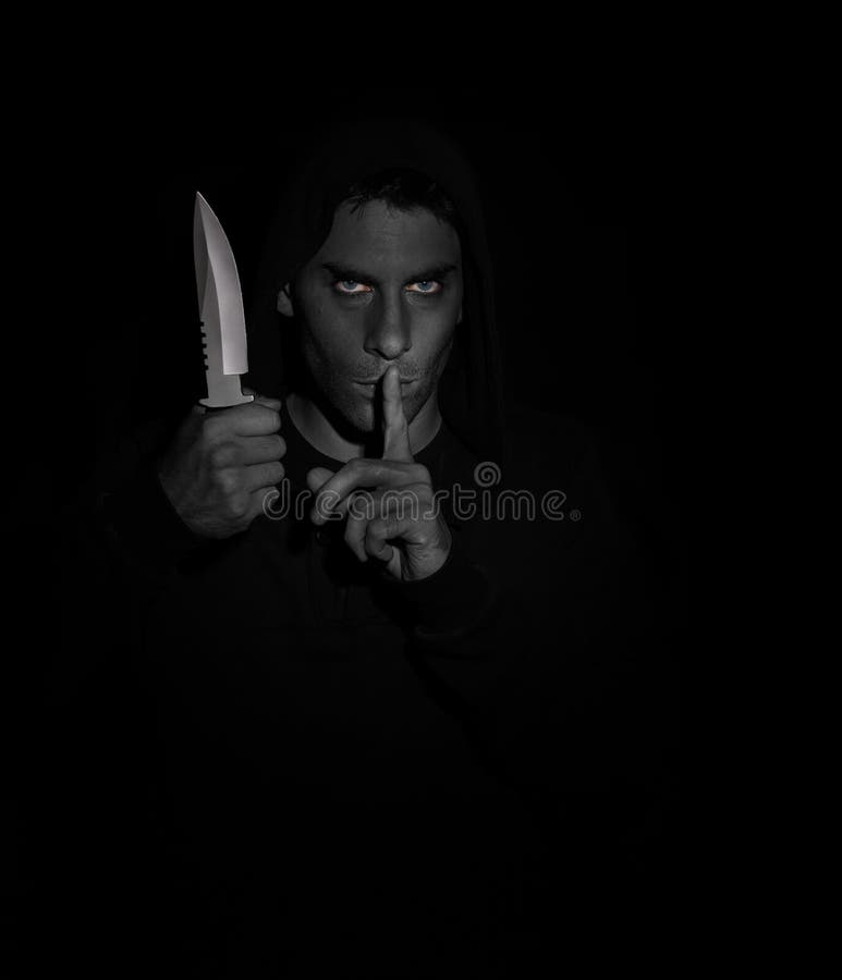 Evil man gesturing silence while holding a knife. Black and white, eyes in color. Evil man gesturing silence while holding a knife. Black and white, eyes in color