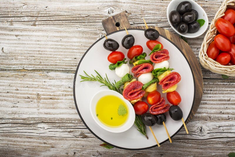 Здоровая закуска: рт-моча kebabs на пикнике с томатами, моццарелле, салями, черных оливках, базилике, tortellini стоковое фото rf Здоровая закуска: рт-моча kebabs на пикнике с томатами, моццарелле, салями, черных оливках, базилике, tortellini стоковое фото rf