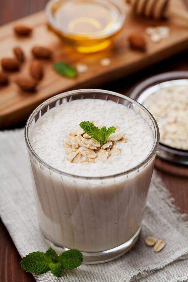 Здоровый завтрак smoothie или milkshake банана с овсами и медом украсил листья мяты стоковые фото Здоровый завтрак smoothie или milkshake банана с овсами и медом украсил листья мяты стоковые фото