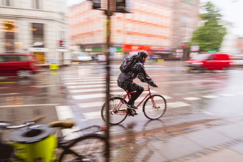 Man is commuting on bicycle during heavy rain. Copenhagen, Denmark. Bicycling is common way of transportation in this city. Man is commuting on bicycle during heavy rain. Copenhagen, Denmark. Bicycling is common way of transportation in this city