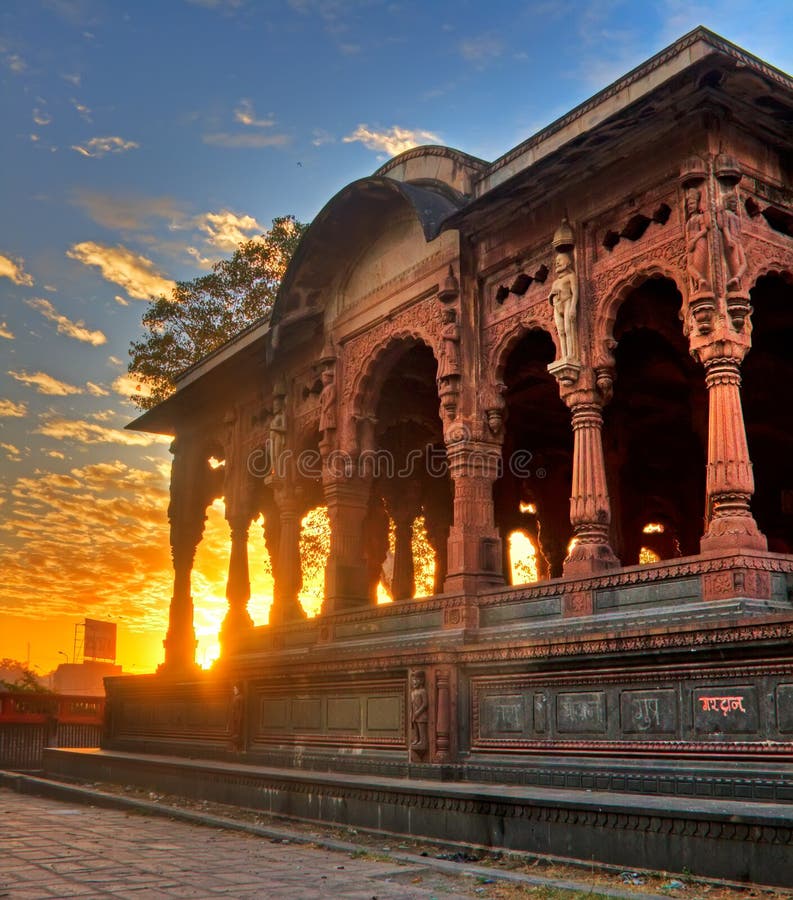 Photo of a temple at Indore called the Chatri taken at the dawn with the sun rising behind it. The Chatri is part of the palace of Indore called Rajwada and were build by the Holkar Dynasti and identify the city of Indore, India. Photo of a temple at Indore called the Chatri taken at the dawn with the sun rising behind it. The Chatri is part of the palace of Indore called Rajwada and were build by the Holkar Dynasti and identify the city of Indore, India