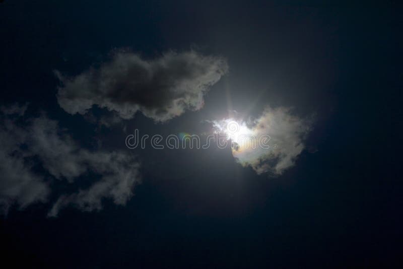 Dark clouds in a very sunny sky with a sun flare, very under exposed. Dark clouds in a very sunny sky with a sun flare, very under exposed
