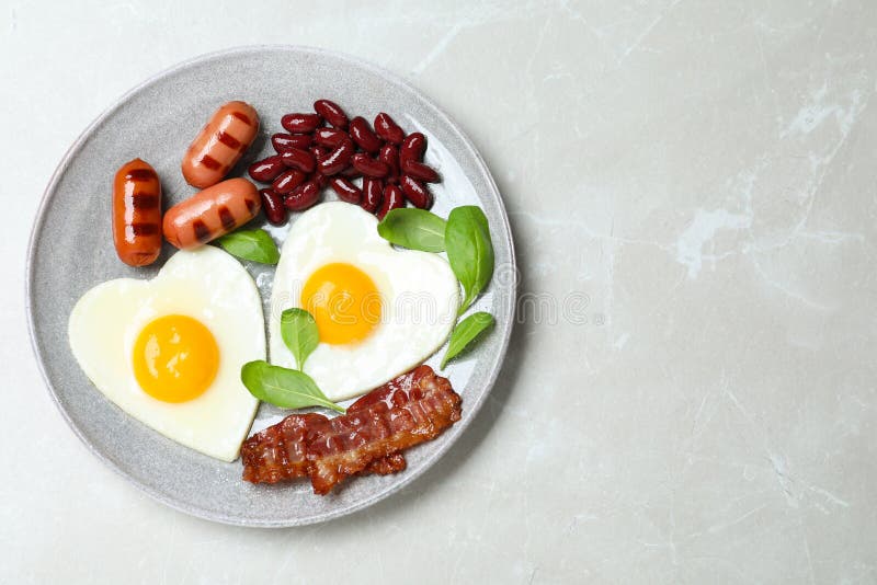 Завтрак со вкусом и жаркими яйцами в форме сердца на столе, вид сверху Пространство для текста стоковое фото Завтрак со вкусом и жаркими яйцами в форме сердца на столе, вид сверху Пространство для текста стоковое фото