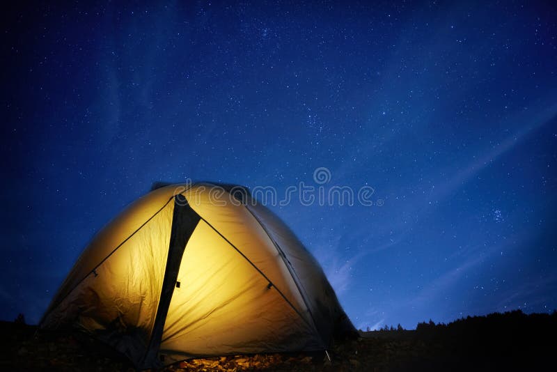 Illuminated yellow camping tent under stars at night. Illuminated yellow camping tent under stars at night