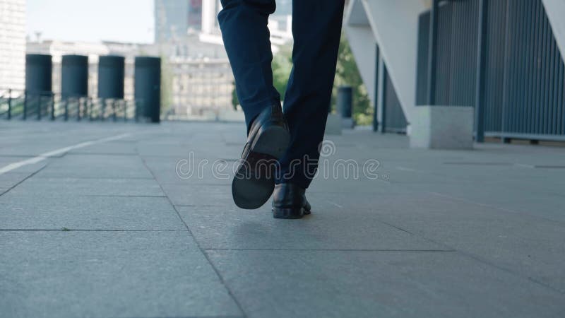 задний вид ноги бизнесмена. уверенный человек в кожаных туфлях и формальном костюме идет по центру