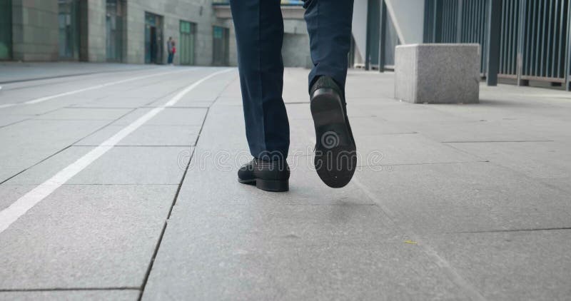 задний вид уверенного человека в кожаных туфлях и официальный костюм начинают идти по улице делового района. задний