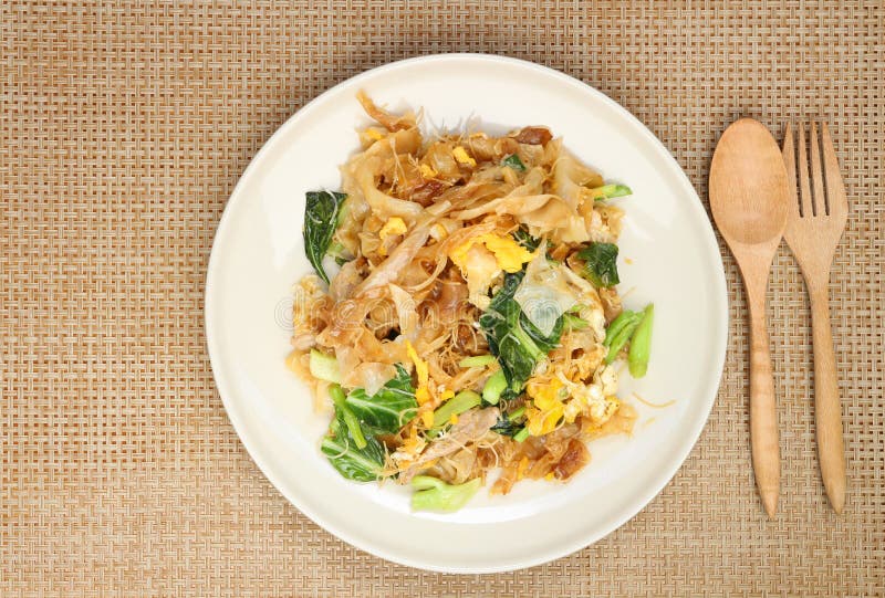 Fried noodle with pork and broccoli in black bowl place on wooden table with copy space for your text and design. Concept be used for menu presentation at cafe and restaurant. top view. Fried noodle with pork and broccoli in black bowl place on wooden table with copy space for your text and design. Concept be used for menu presentation at cafe and restaurant. top view