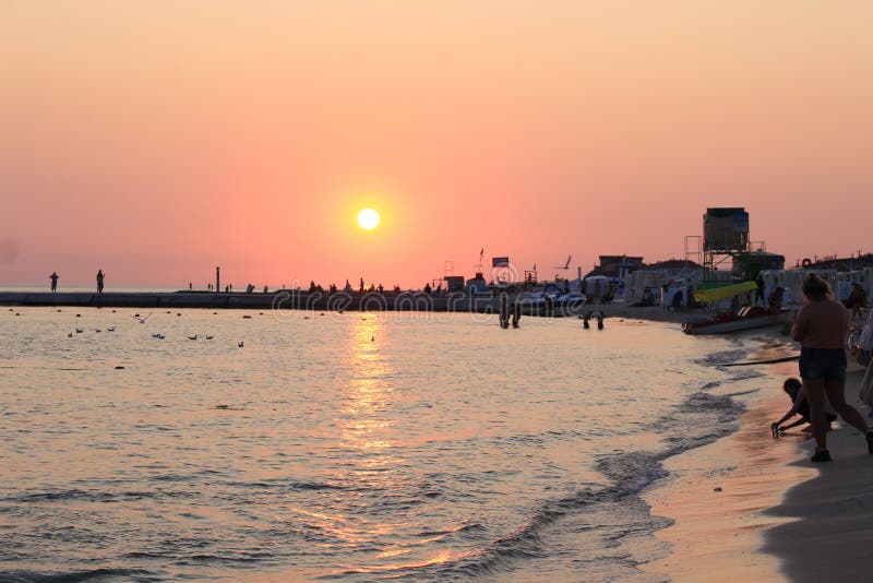 закат красит небо и море в тени красного. чайки летают на фоне ...