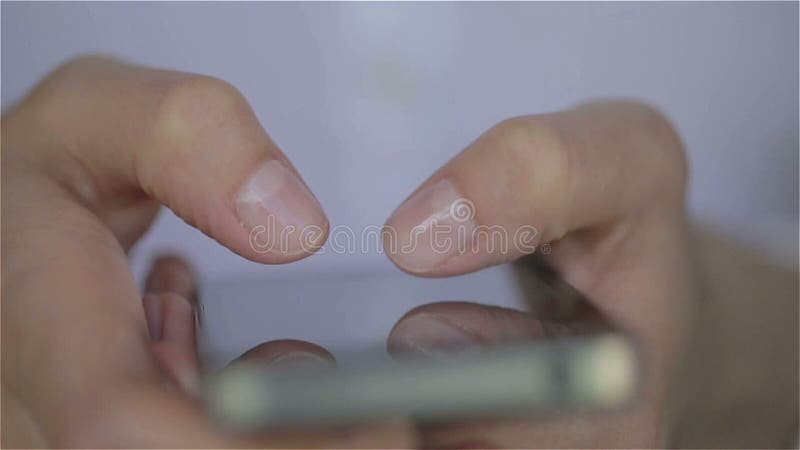 Закройте вверх пальцев платья молодой женщины белых печатая на ее smartphone видеоматериал