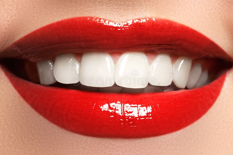 Close up beauty portrait view of a young woman natural smile with red lips. Classic beauty detail. Red lipstick and white teeth. Closeup of woman smiling with prefect white teeth. Close up beauty portrait view of a young woman natural smile with red lips. Classic beauty detail. Red lipstick and white teeth. Closeup of woman smiling with prefect white teeth.