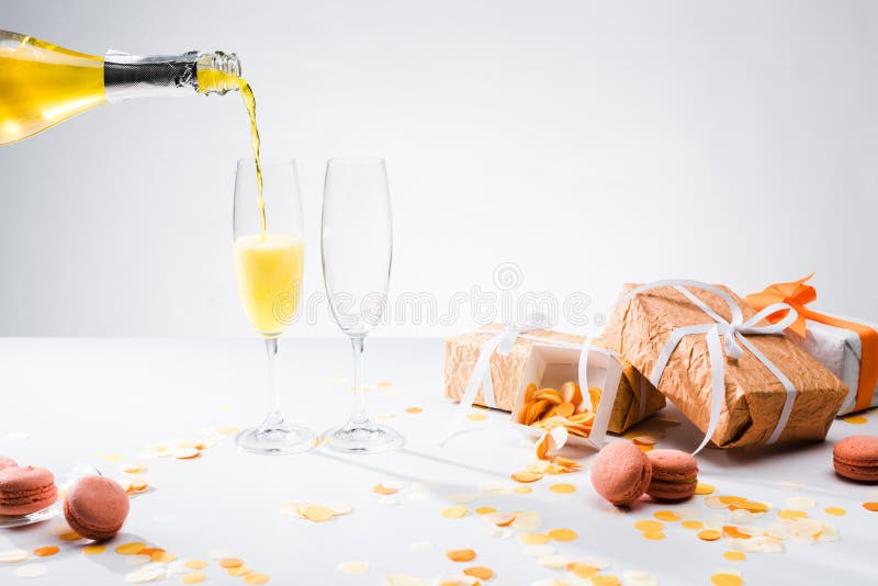 закройте вверх по взгляду лить желтое шампанское в процесс стекел, macarons и аранжированные подарки стоковые изображения rf закройте вверх по взгляду лить желтое шампанское в процесс стекел, macarons и аранжированные подарки стоковые изображения rf