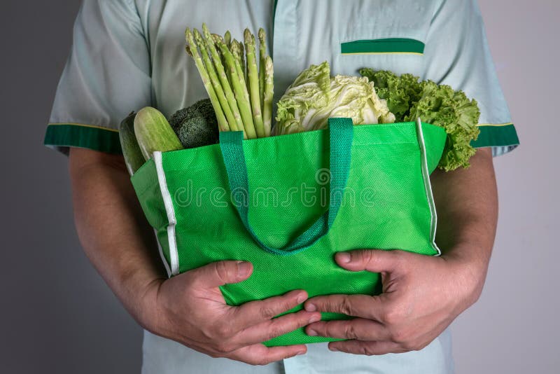 Закройте вверх по руке держа зеленую продуктовую сумку смешал органическое gre стоковая фотография
