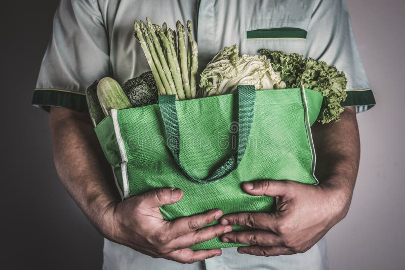 Закройте вверх по руке держа зеленую продуктовую сумку смешал органический g стоковое изображение rf