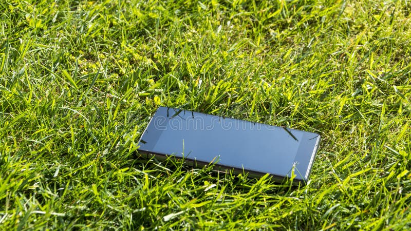 Закройте вверх потерянного smartphone - лежащ в траве на солнечном дне стоковое изображение rf