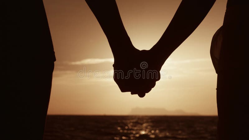 закройте руки влюбленной паре, держась за руки на фоне солнца. семья на закате. мужчина и женщина
