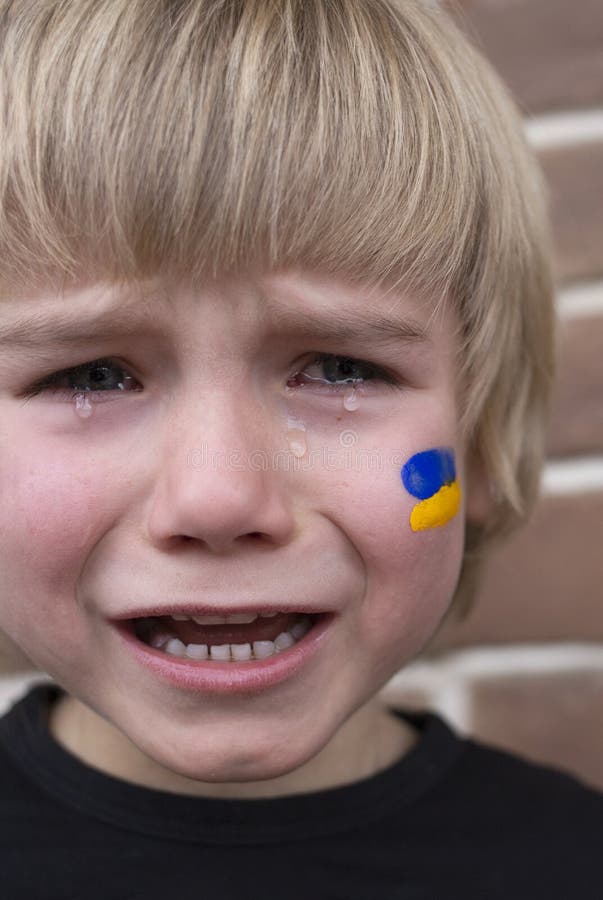 закрытие лица испуганного плачущего украинского мальчика с желто-голубым украинским флагом, нарисованным на щеке стоковая фотография rf