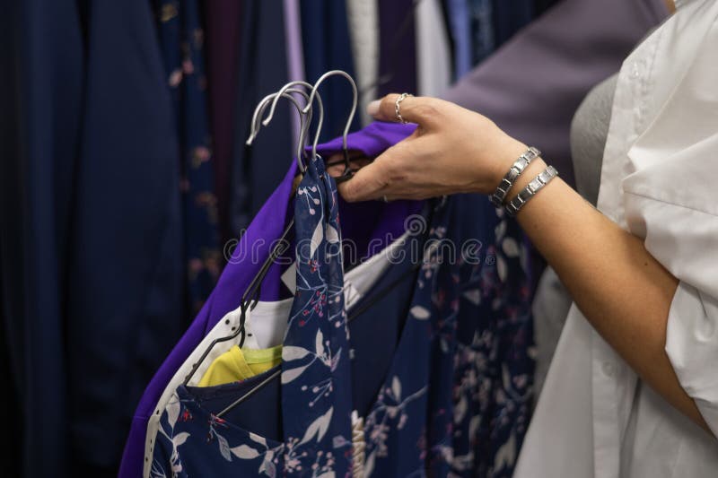 Close-up of woman& x27;s hands with hangers in a clothing store. Close-up of woman& x27;s hands with hangers in a clothing store