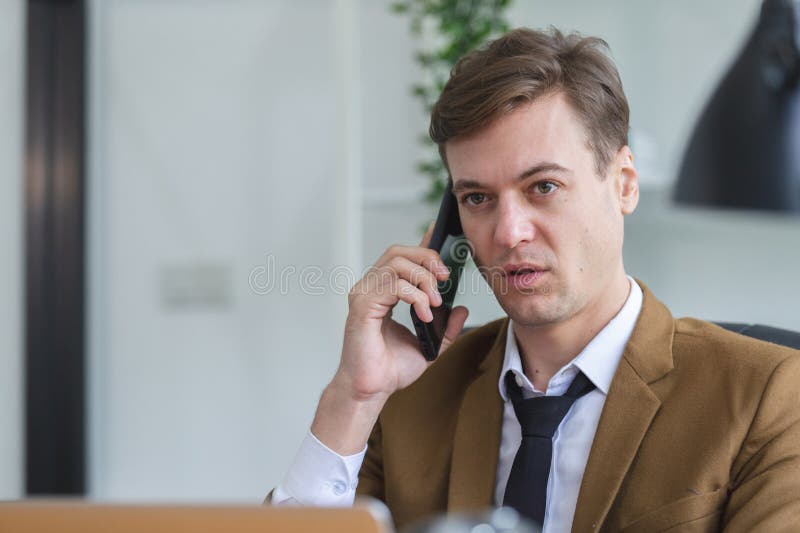 Закрыть бизнесмен, звонящий по телефону за офисным столом. управляющий мобильным телефоном. красивый менеджер сидит в офисе стоковое изображение