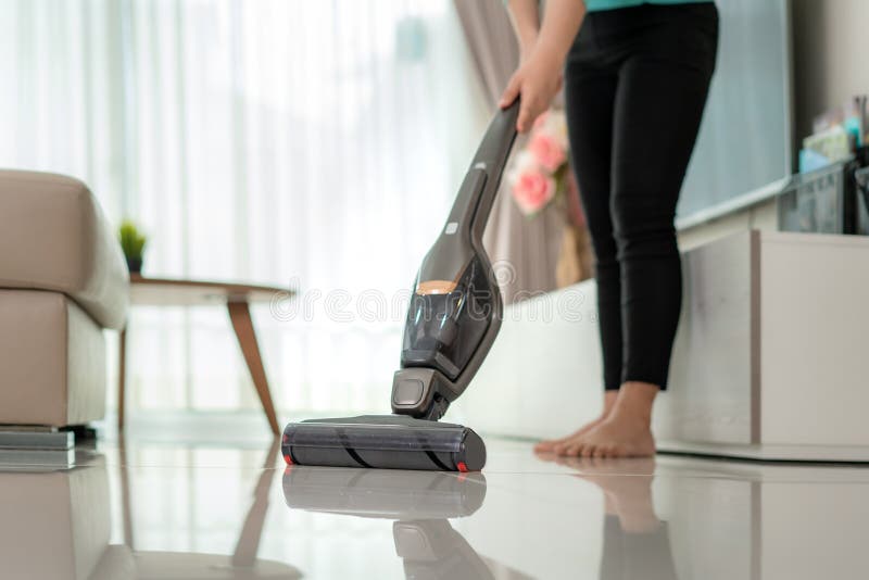 Close up of  woman wearing casual clothes  is cleaning house floor in living room using the vacuum cleaner at home during Staying at home using free time about their daily housekeeping routine. Close up of  woman wearing casual clothes  is cleaning house floor in living room using the vacuum cleaner at home during Staying at home using free time about their daily housekeeping routine.