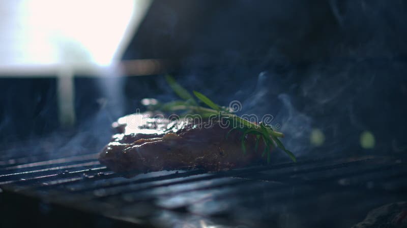 Закрыть мясной стейк, курящий на бк-гриле в темноте. дым движется медленно, как пища акции видеоматериалы