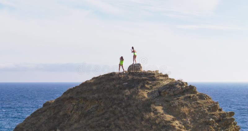 замедленное движение молодых взрослых женщин в купальниках, танцующих тверк на холме на фоне моря. молодежной культуры видеоматериал