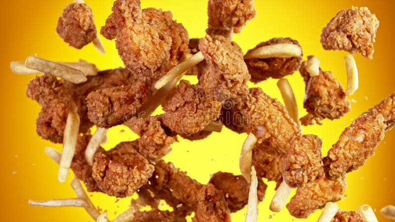 заморозить движение кусочков жареных кур и картошки фри стоковые фото