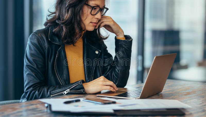 Busy woman sitting on desk and working on laptop. Asian businesswoman working on laptop computer at office. Busy woman sitting on desk and working on laptop. Asian businesswoman working on laptop computer at office.