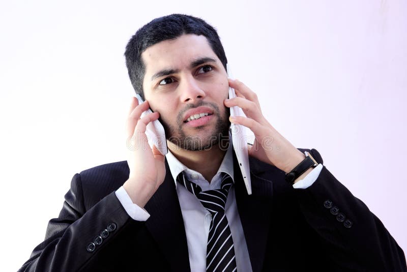 Image of busy arab business man wearing black suit and talking wih 2 phones. Image of busy arab business man wearing black suit and talking wih 2 phones