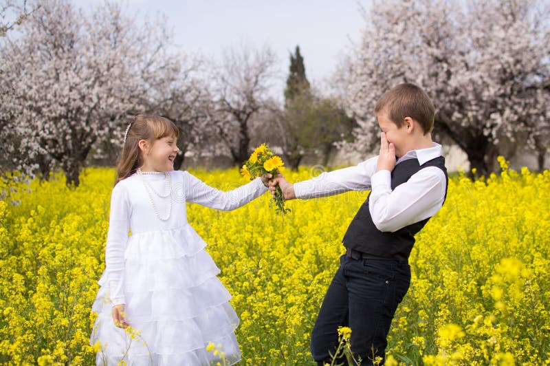 Very shy boy giving girl bouquet of flowers on the beautiful field of yellow flowers. Very shy boy giving girl bouquet of flowers on the beautiful field of yellow flowers.