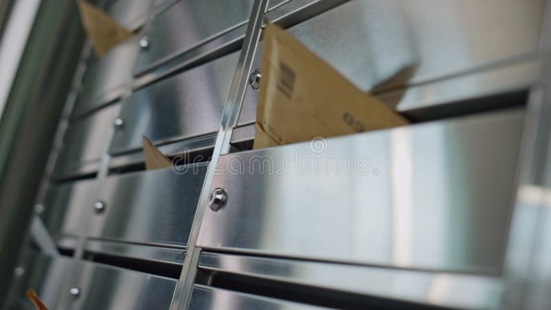 Paper envelopes stuck mailbox closeup. Silver post lockers in building corridor. Yellow bills mails left in postal boxes indoors. Steel modern containers reflecting light. Correspondence spam concept. Paper envelopes stuck mailbox closeup. Silver post lockers in building corridor. Yellow bills mails left in postal boxes indoors. Steel modern containers reflecting light. Correspondence spam concept.