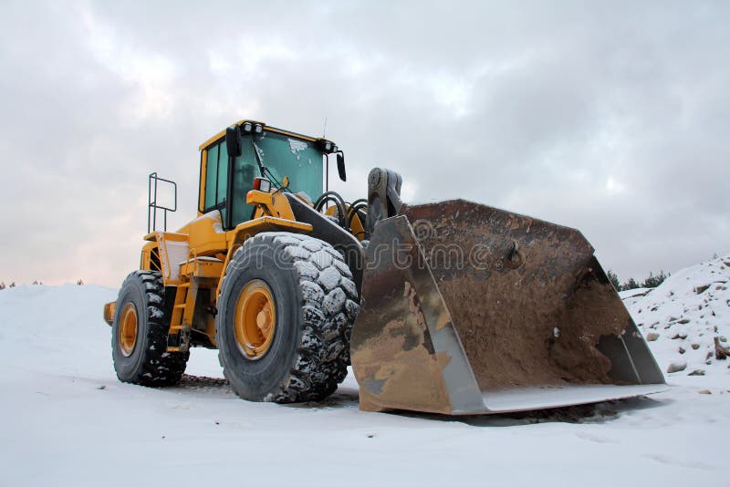 Yellow wheel loader at sand pit in winter snow. Yellow wheel loader at sand pit in winter snow.