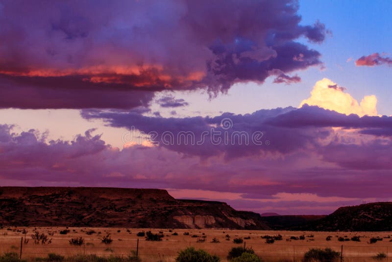 This image of the high plains with clouds was captured at sunset near Santa Fe, New Mexico. The barbed wire fence in the foreground identifies this location as grassland. This photograph was taken in early autumn. This image of the high plains with clouds was captured at sunset near Santa Fe, New Mexico. The barbed wire fence in the foreground identifies this location as grassland. This photograph was taken in early autumn.