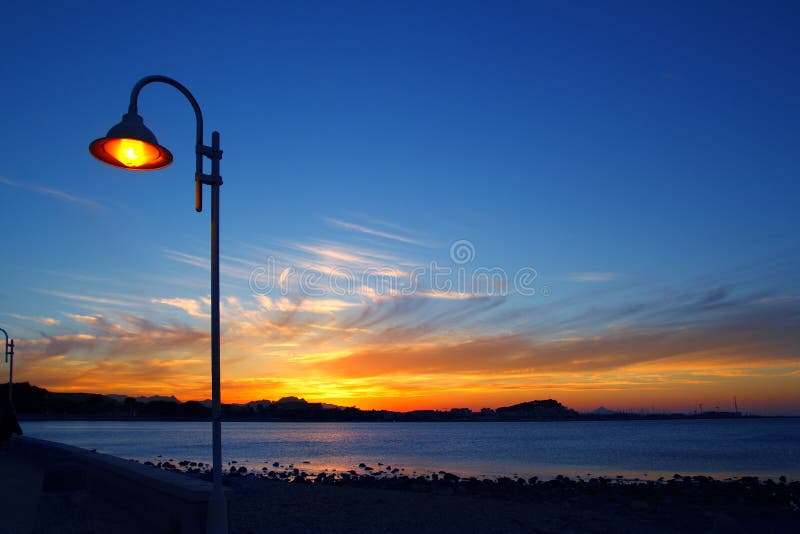 заход солнца seascape голубого lamppost светлооранжевый стоковая фотография заход солнца seascape голубого lamppost светлооранжевый стоковая фотография